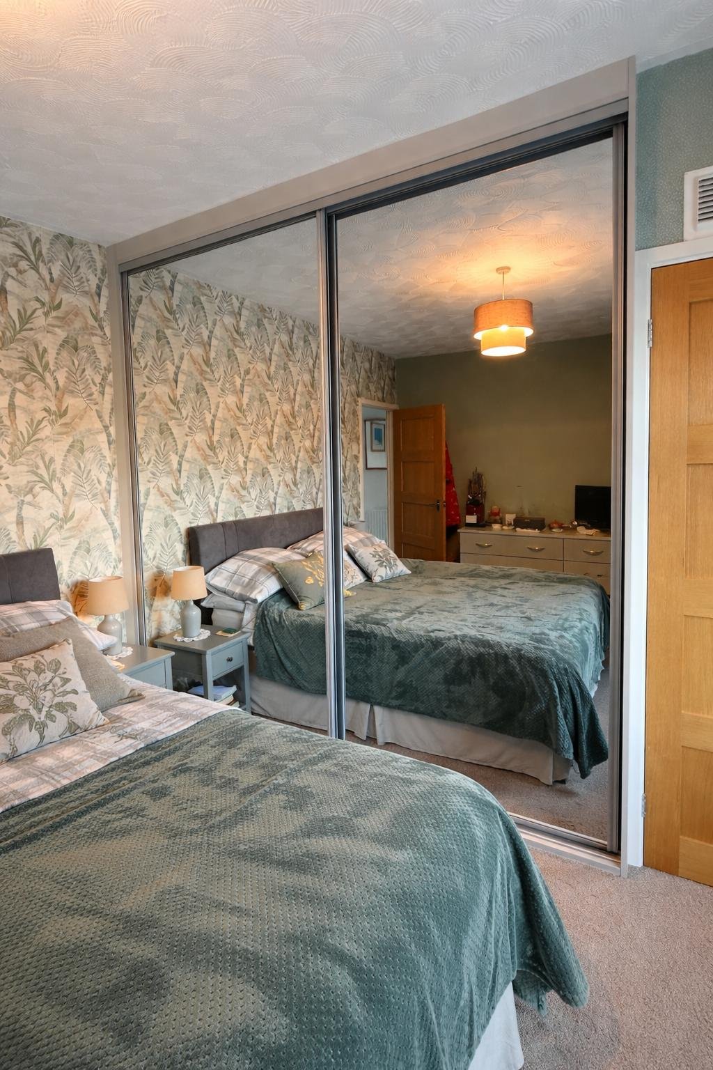 Light grey wood frame with silver profile handles and two full-height mirrored doors.

Made to measure sliding wardrobe fitted wall-to-wall in Merthyr Tydfil for a bright, seamless finish.

Designed and manufactured in our Mountain Ash workshop to ma