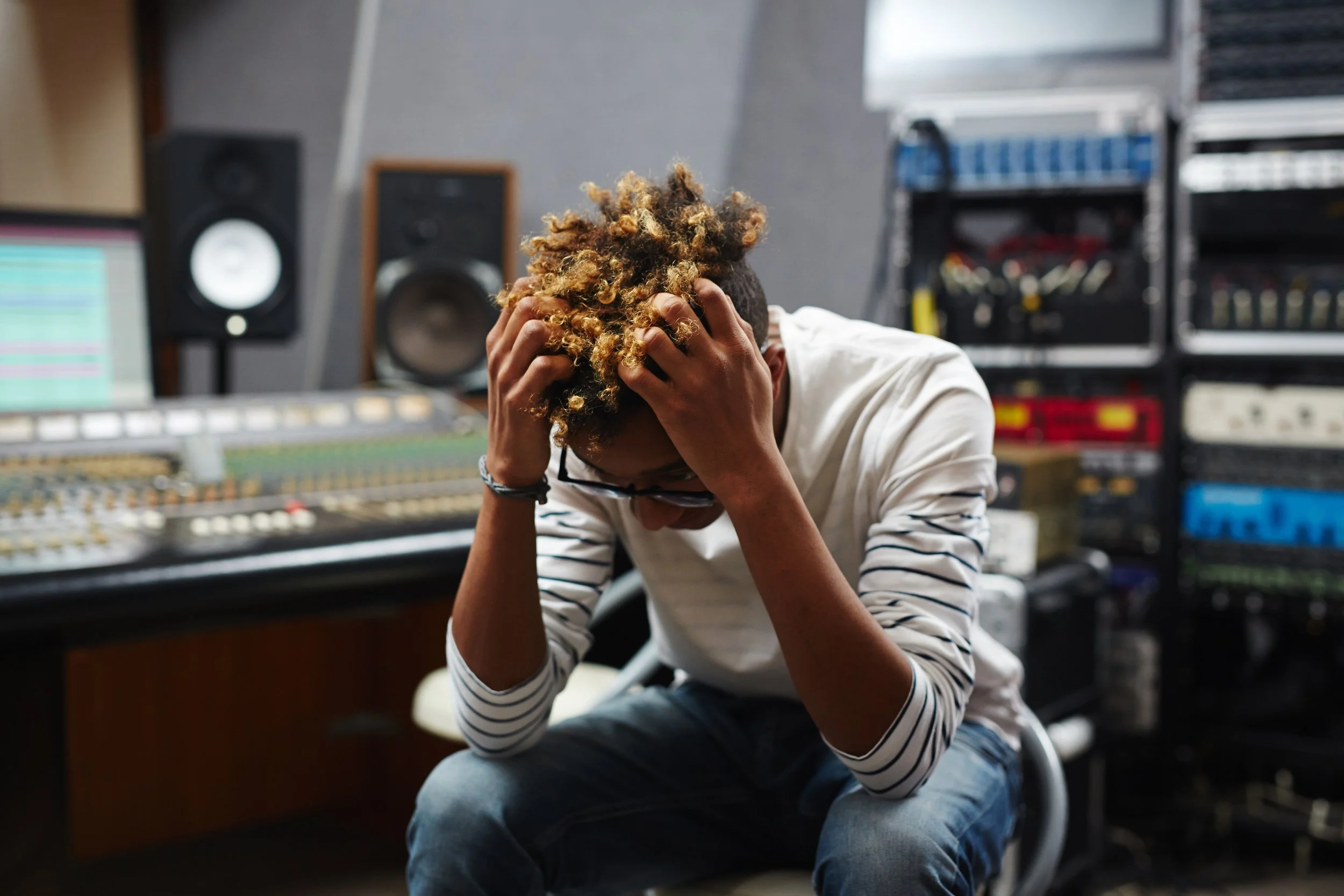 Person sitting in a recording studio holding their head with both hands