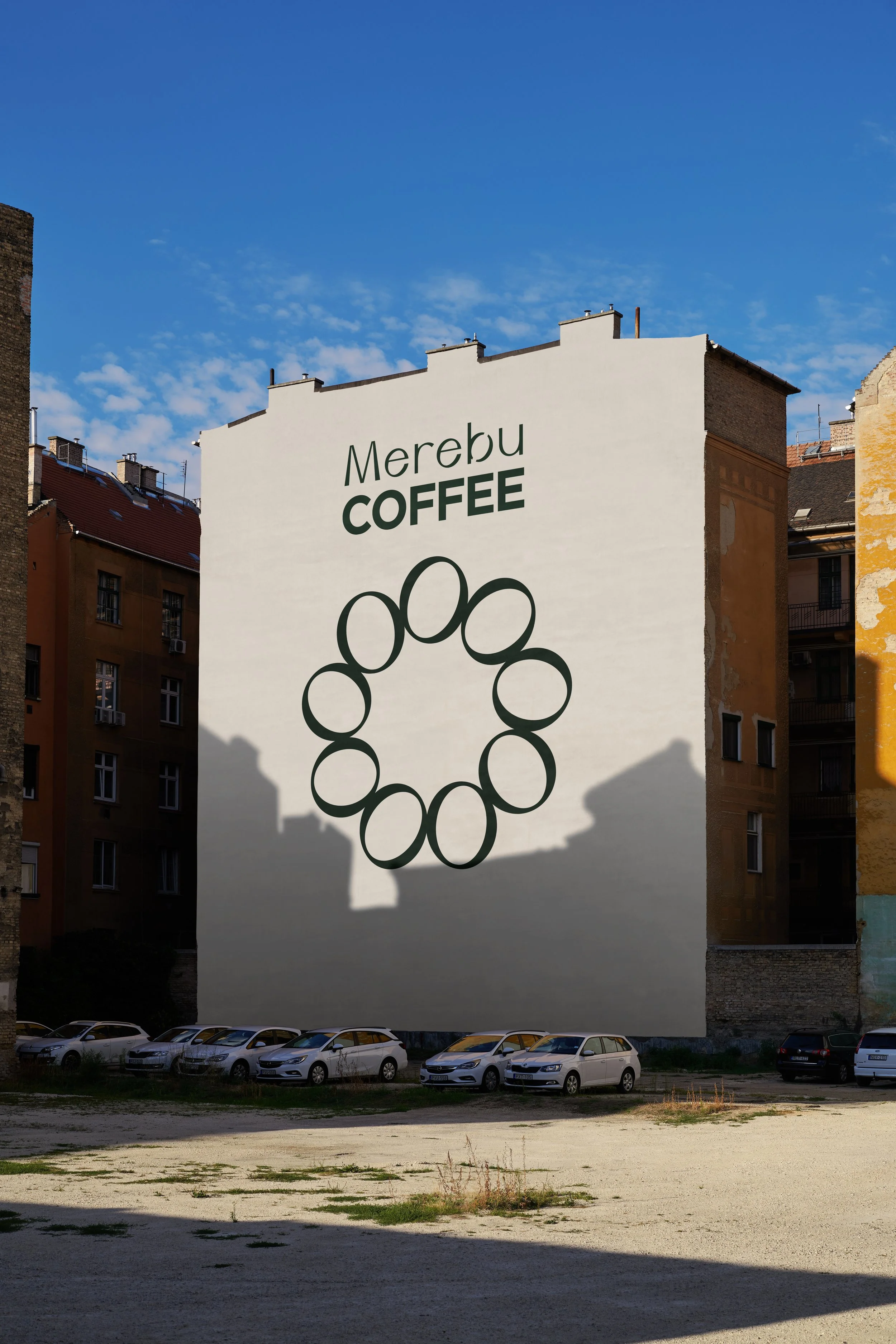 Velkoformátová malba loga (mural) na fasádě budovy. Využití vizuální identity Merebu Coffee v městském prostoru a outdoor reklamě.
