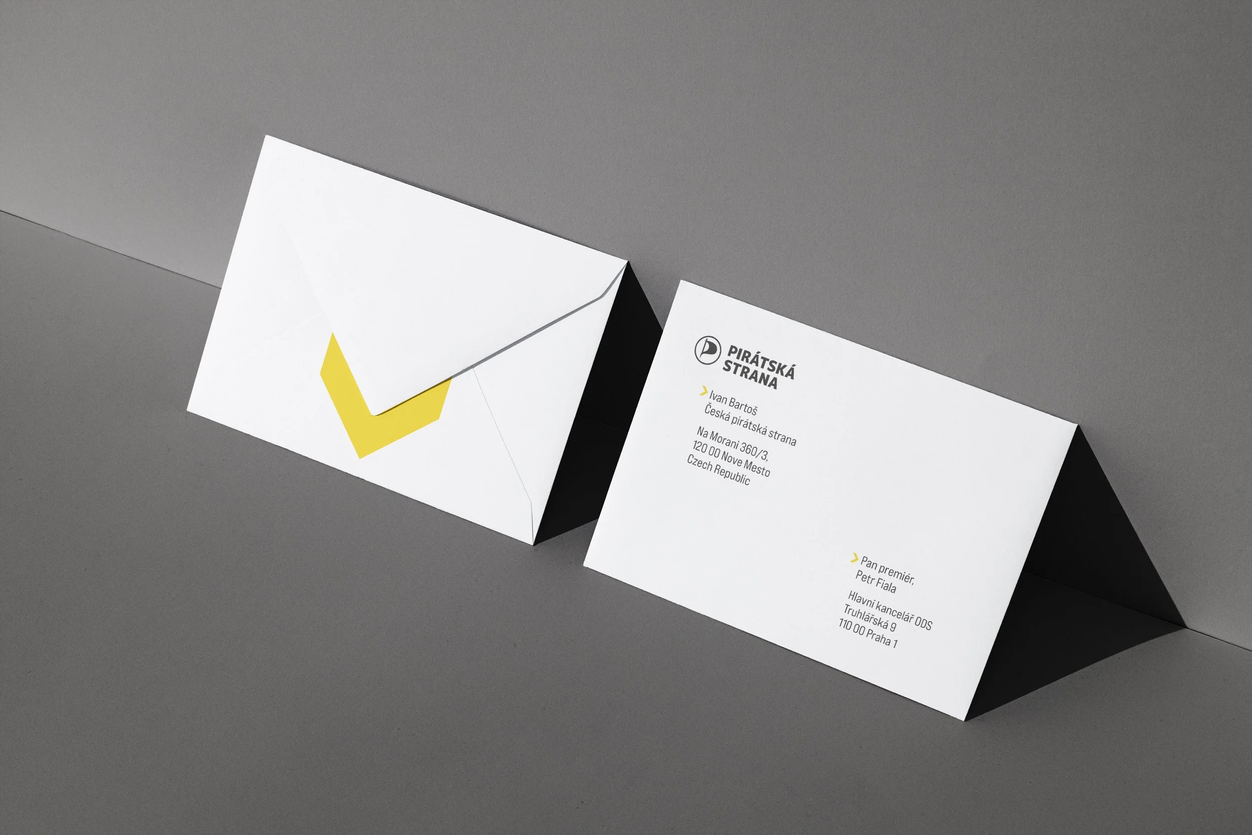 Volební merch a propagační předměty. Bílá plátěná taška a tričko s minimalistickým vzorem šipek. Ukázka aplikace brandingu na textil a vizitky.