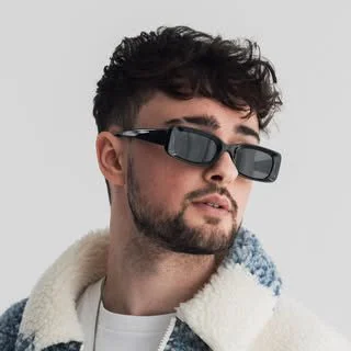 A young man wearing sunglasses and a white jacket with a fluffy collar.