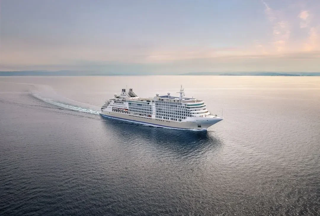 A Silversea suite interior with the balcony doors open to the sea and daylight across the room.