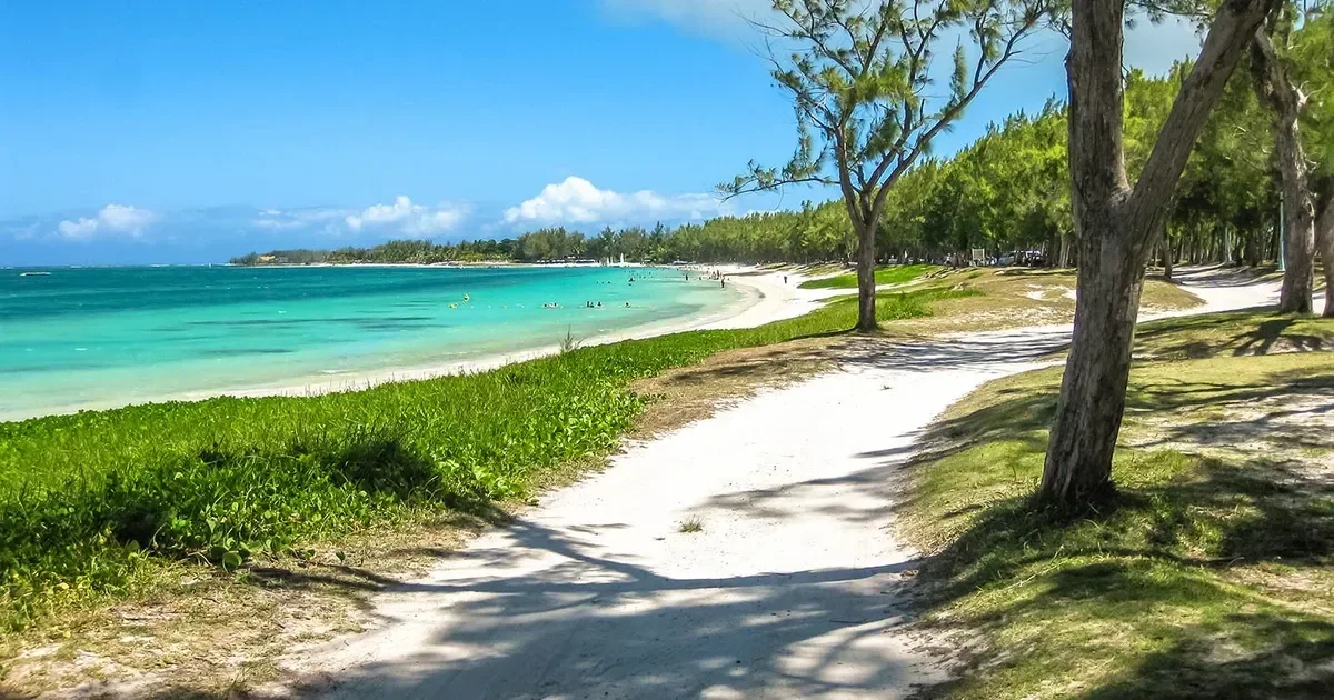 A wide turquoise lagoon bounded by a pale coral reef line, calm water fading to deep blue beyond the reef break.