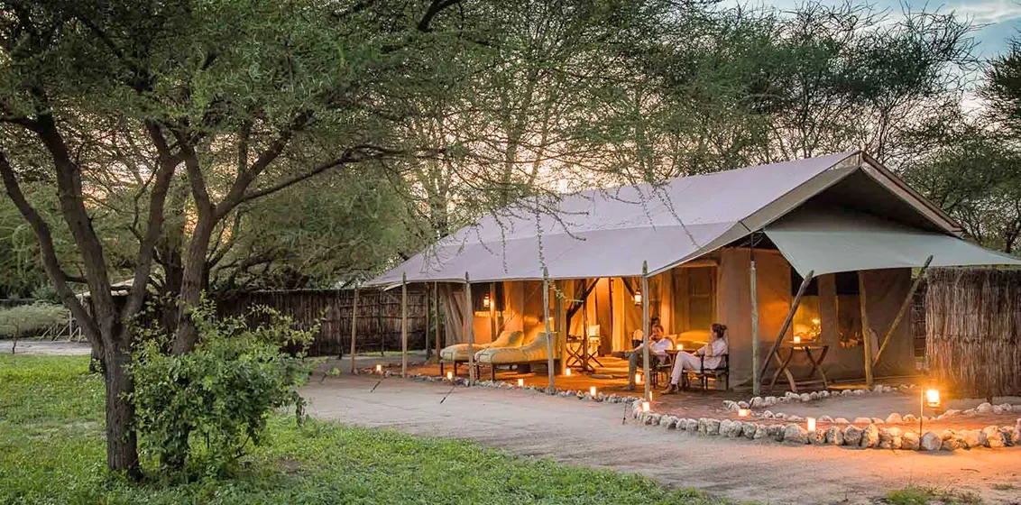 Wide editorial view of an Auberge Safari lodge set in Tanzania's northern wildlife circuit, with the property visible in mid-ground and the savannah landscape stretching to the horizon.