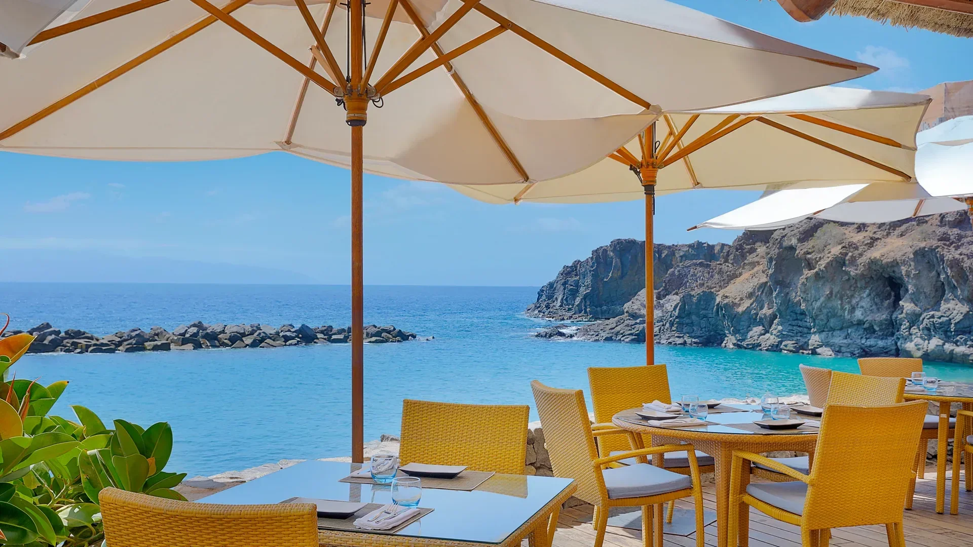 Tables under white parasols at the beach club at The Ritz-Carlton, Abama in Tenerife, looking out over the Atlantic.