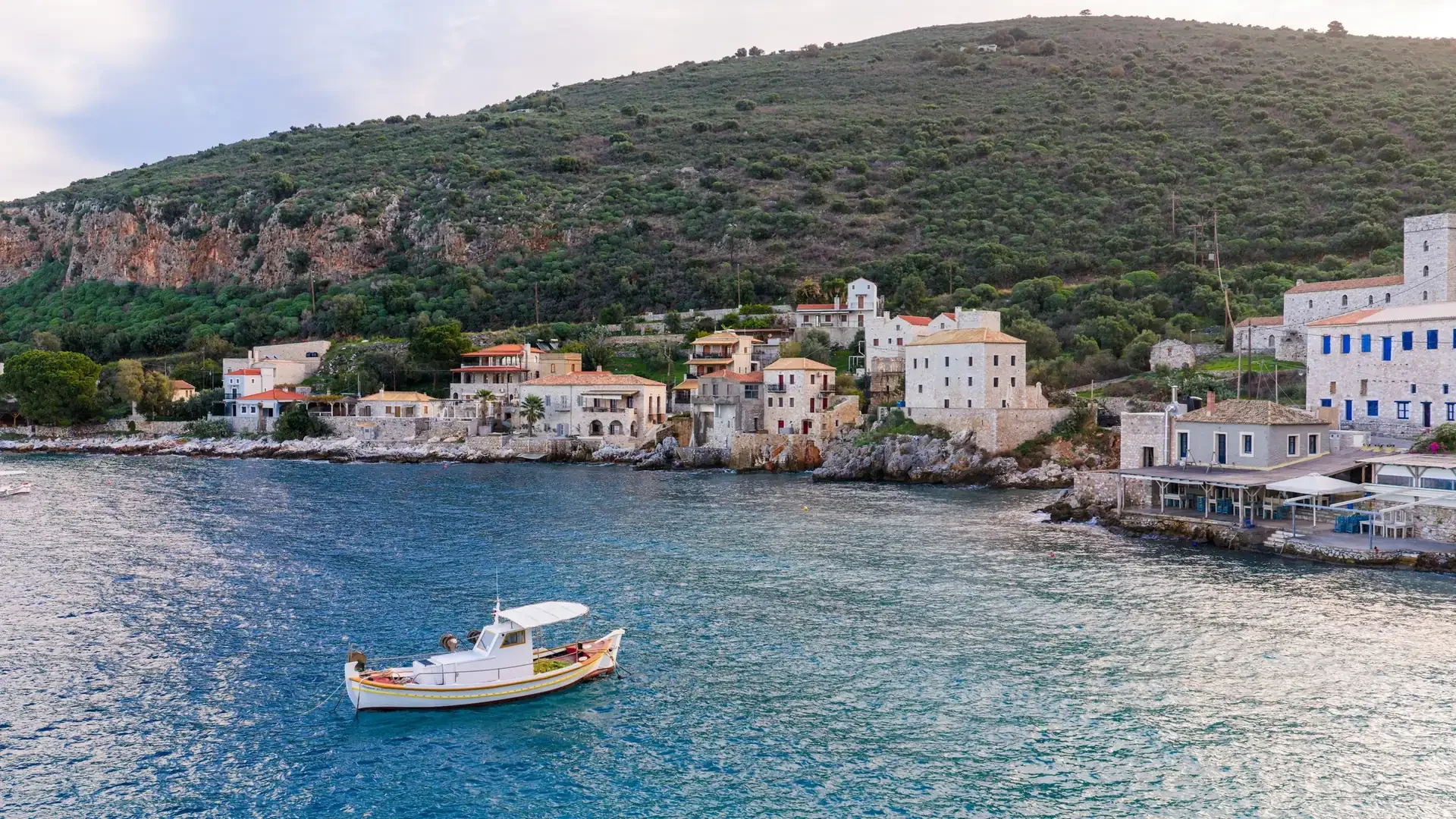 A wide, quiet stretch of Mediterranean coastline in low autumn light, calm water, no crowds, no hotel signage.