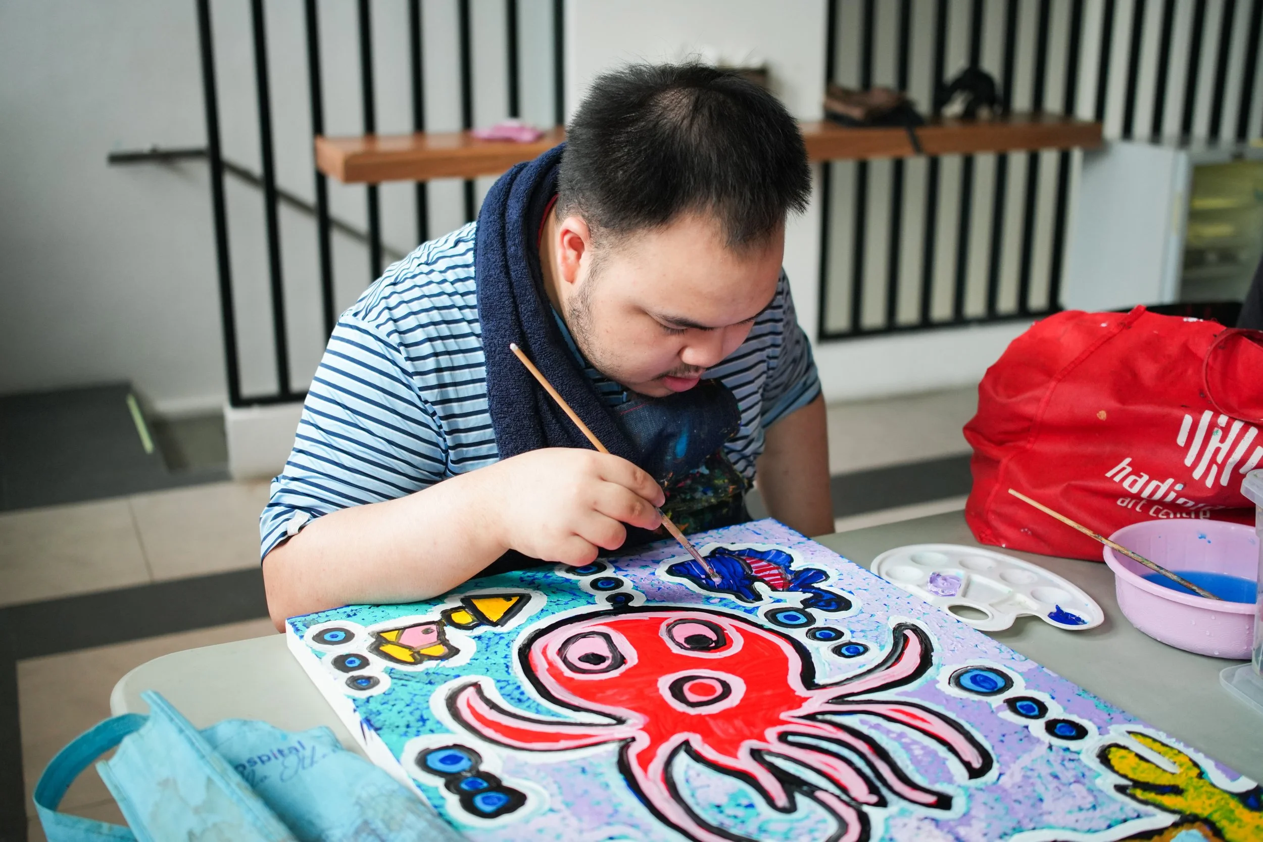 Participant in PUPA Center’s art program developing creativity, concentration, and fine motor skills through a structured painting activity in an inclusive learning environment.