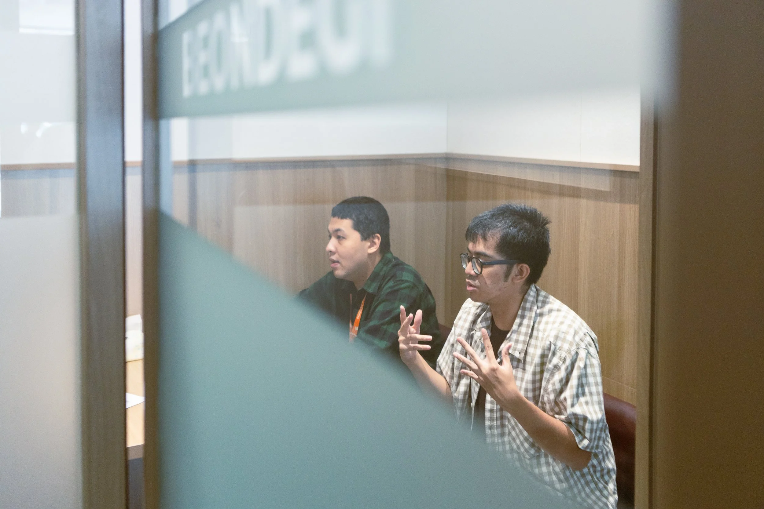 Two young adults at PUPA Center engaged in a focused one-on-one discussion, practicing communication and social skills in a supportive, inclusive learning environment.