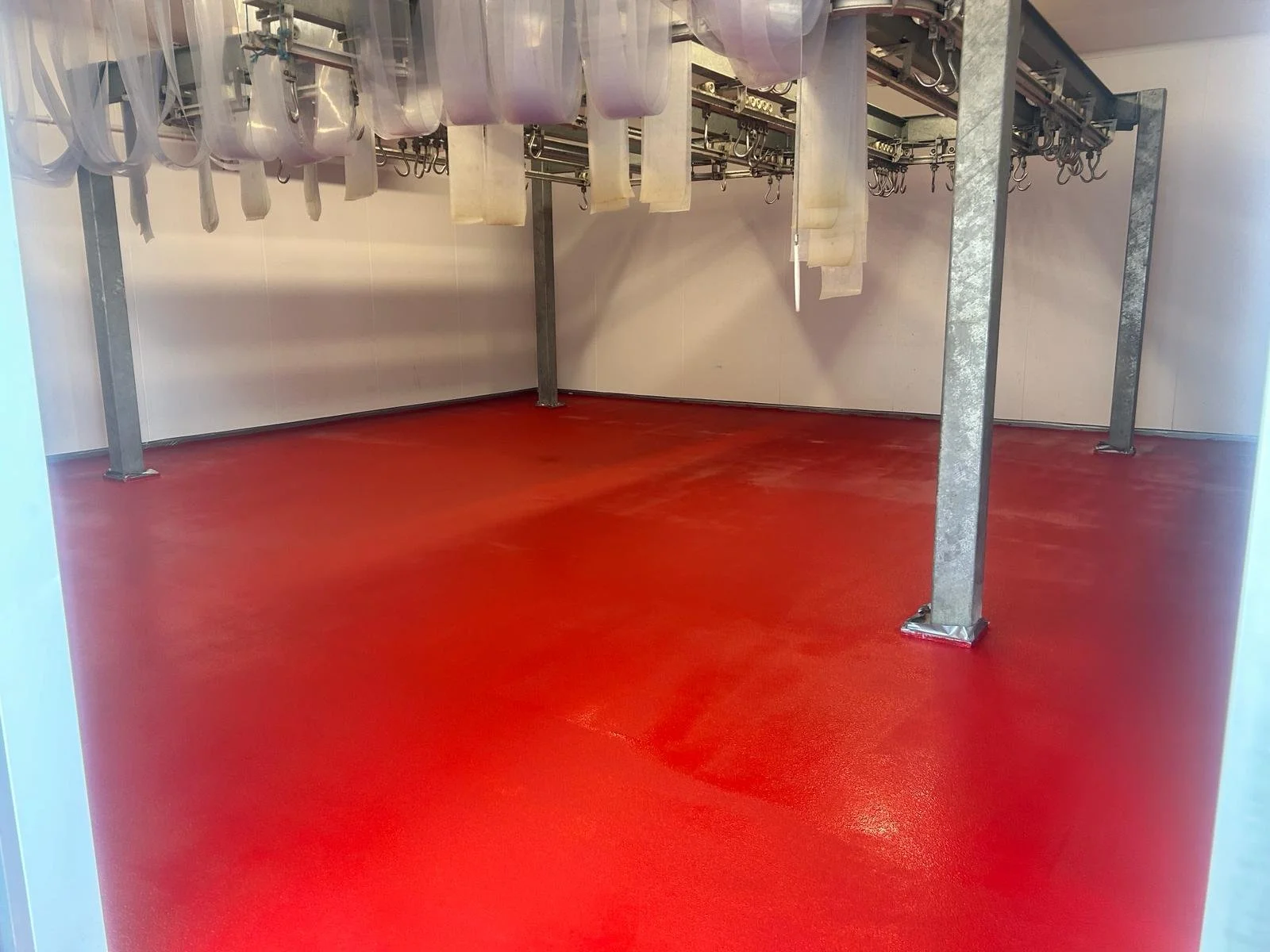 Empty room with red flooring and metal equipment hanging from the ceiling.Resin floors The Wye Valley, Herefordshire, South Wales, West Midlands, west, cardiff, birmingham, bristol