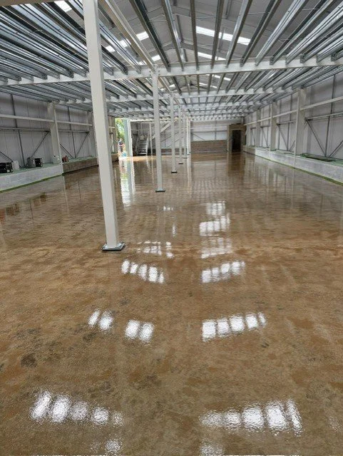 Empty industrial warehouse with a shiny polished concrete floor, metal support beams, and a partially open ceiling.Resin floors The Wye Valley, Herefordshire, South Wales, West Midlands, west, cardiff, birmingham, bristol 