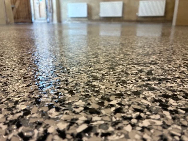 Close-up of a polished terrazzo floor with speckled black, white, and gray chips in an indoor setting.Resin floors The Wye Valley, Herefordshire, South Wales, West Midlands, west, cardiff, birmingham, bristol