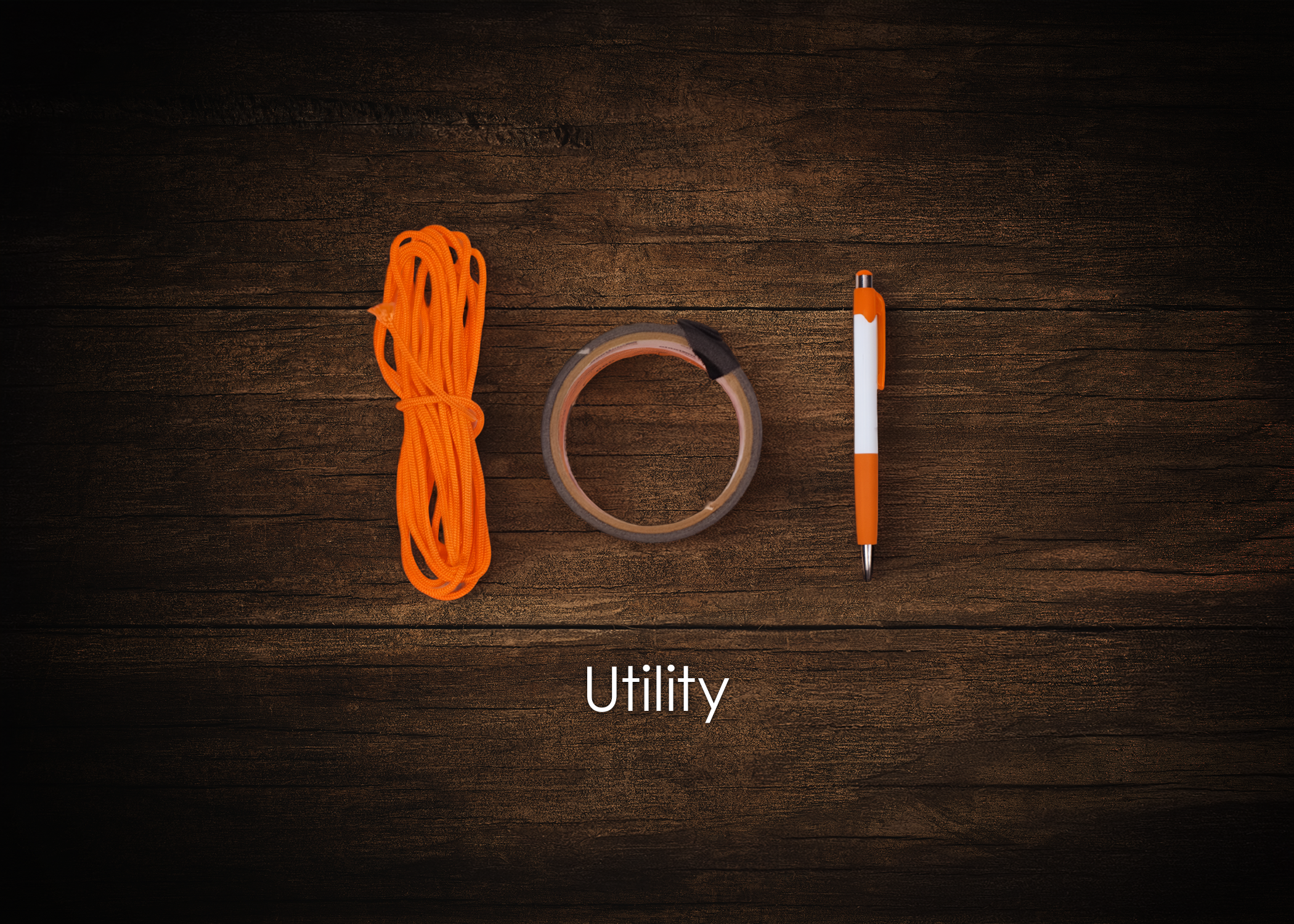 Flat lay of a bundle of orange shoelaces, a roll of clear tape, and a white and orange pen on a wooden surface, with the word 'Utility' written below.