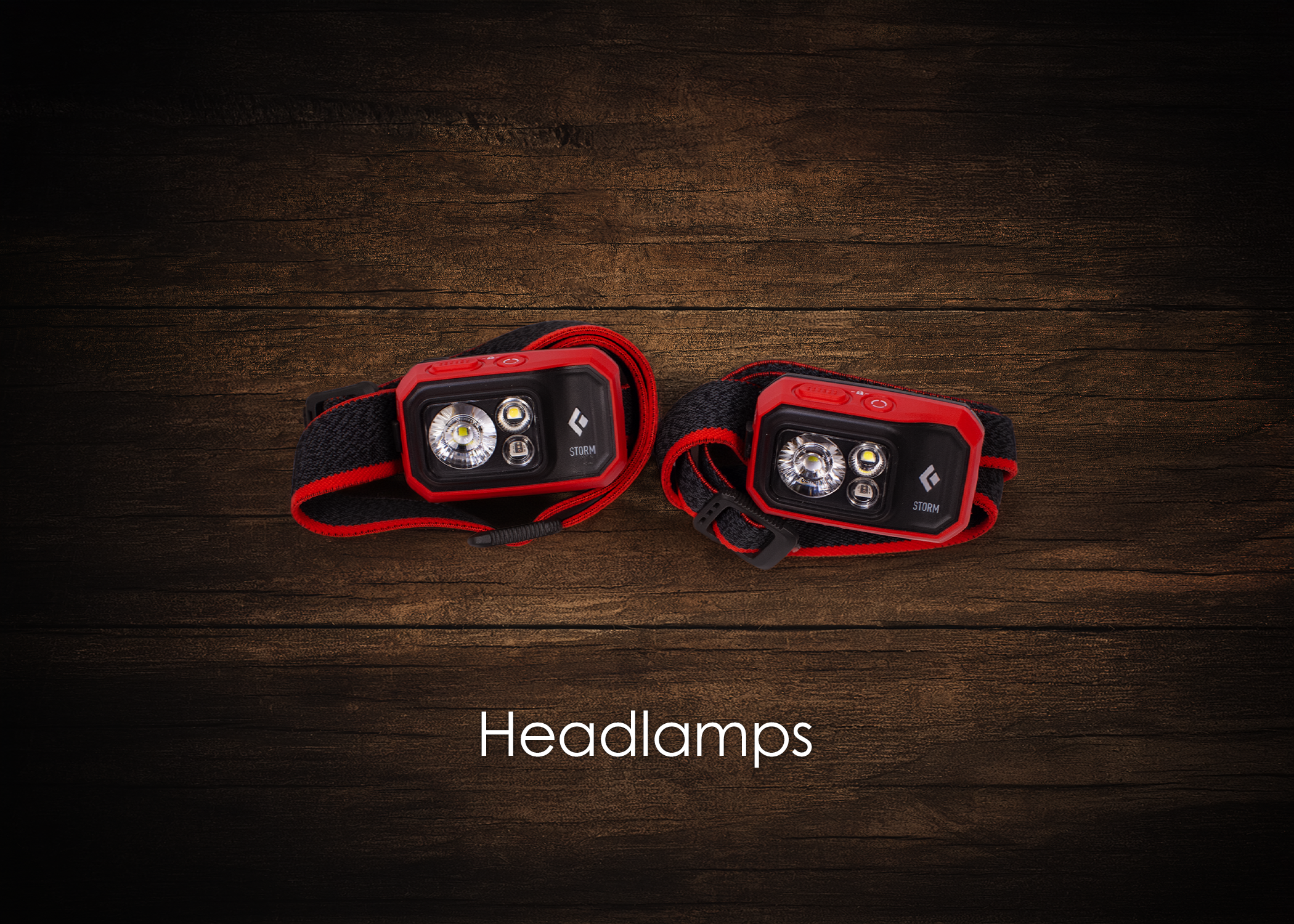 Two black and red headlamps with adjustable straps on a wooden surface, labeled "Headlamps."