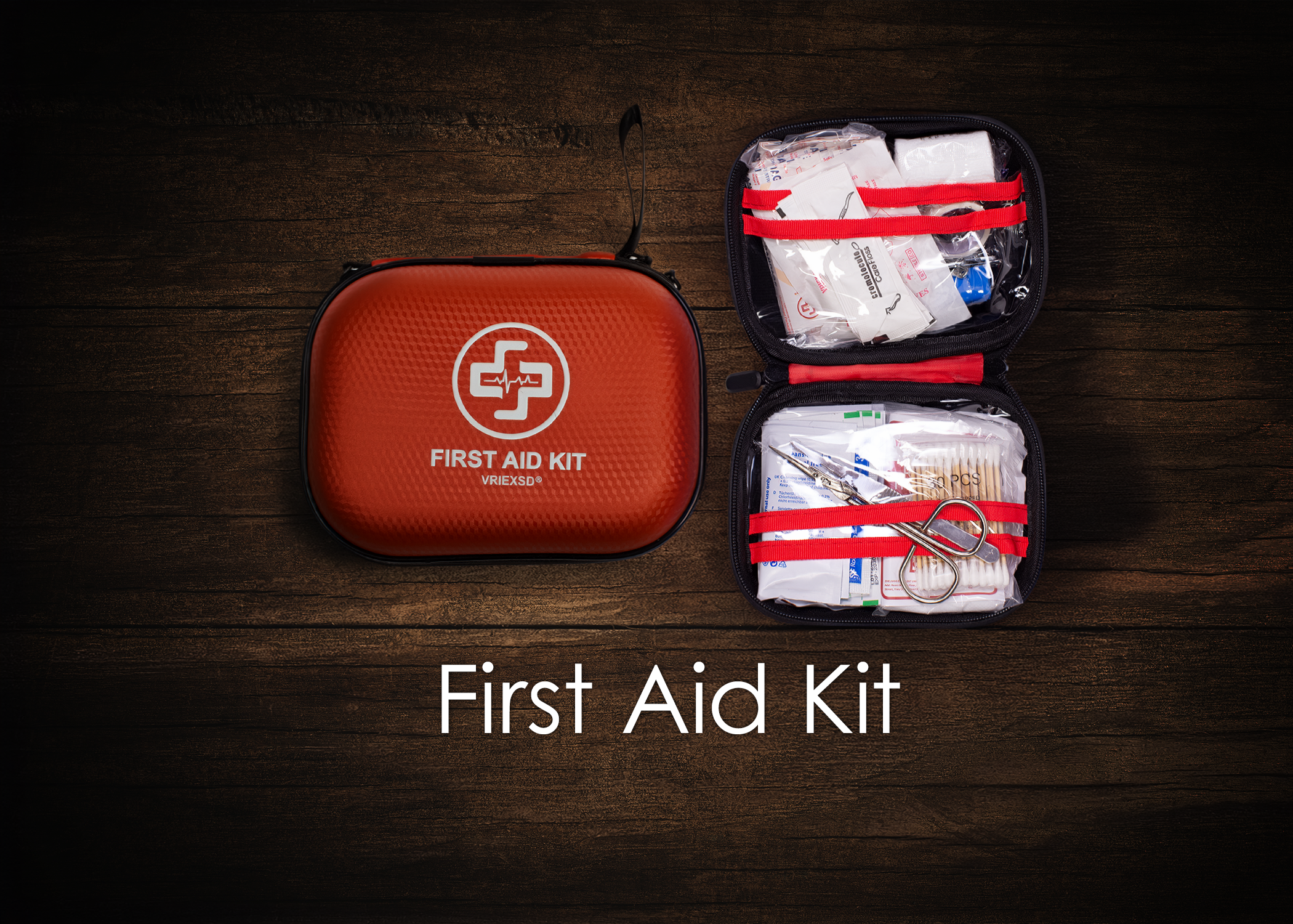 A red first aid kit box with white medical cross logo and text, open to reveal various first aid supplies such as bandages, gauze, scissors, and medical tape, arranged on a dark wooden surface.