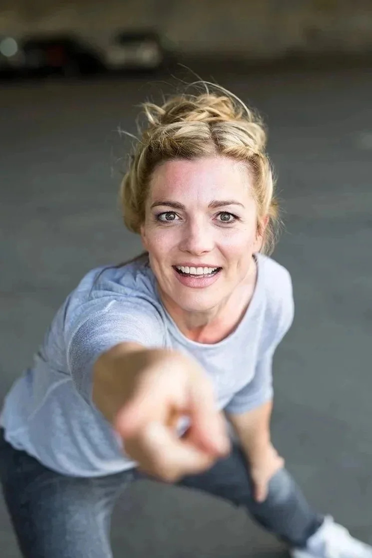 Junge Frau macht einen freundlichen Blick und zeigt mit dem Finger nach oben, während sie nach vorne schaut