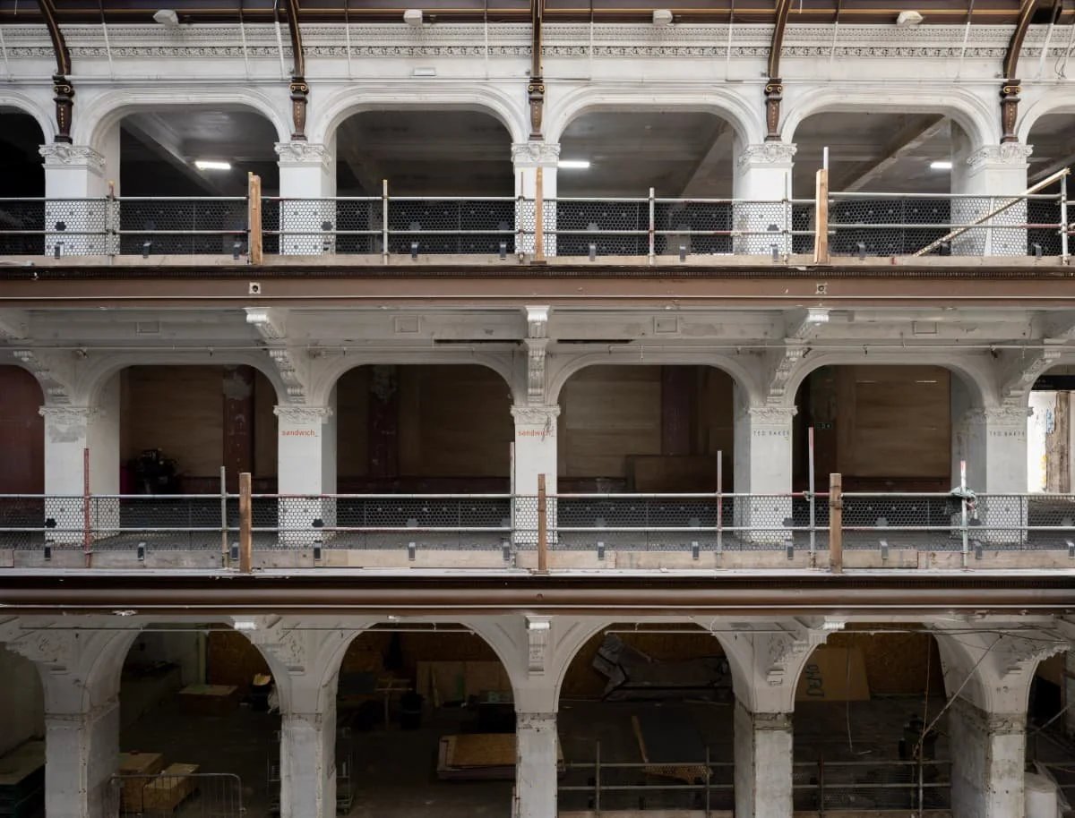 An interior of a multi-floor building under construction with ornate archways and railing, no furniture or occupants visible.