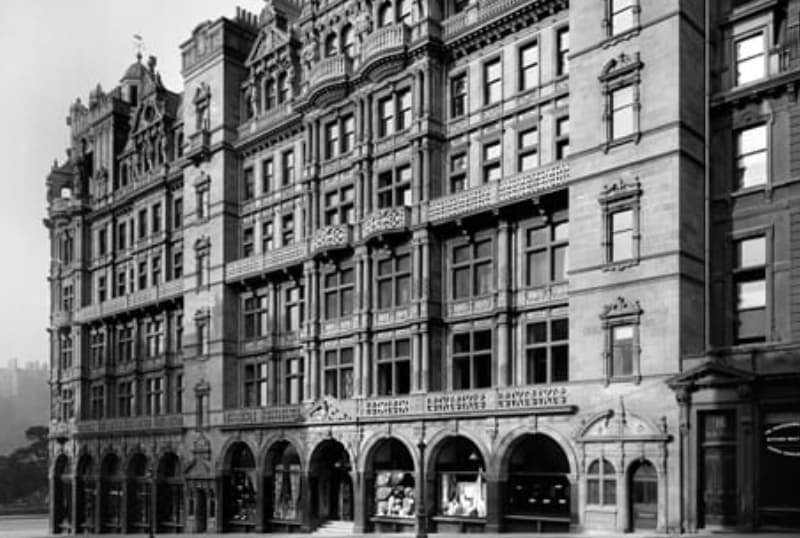 Black and white photo of an ornate purpose built Jenner Building with arched ground-floor entrances, decorative window frames, and balconies in 1895.