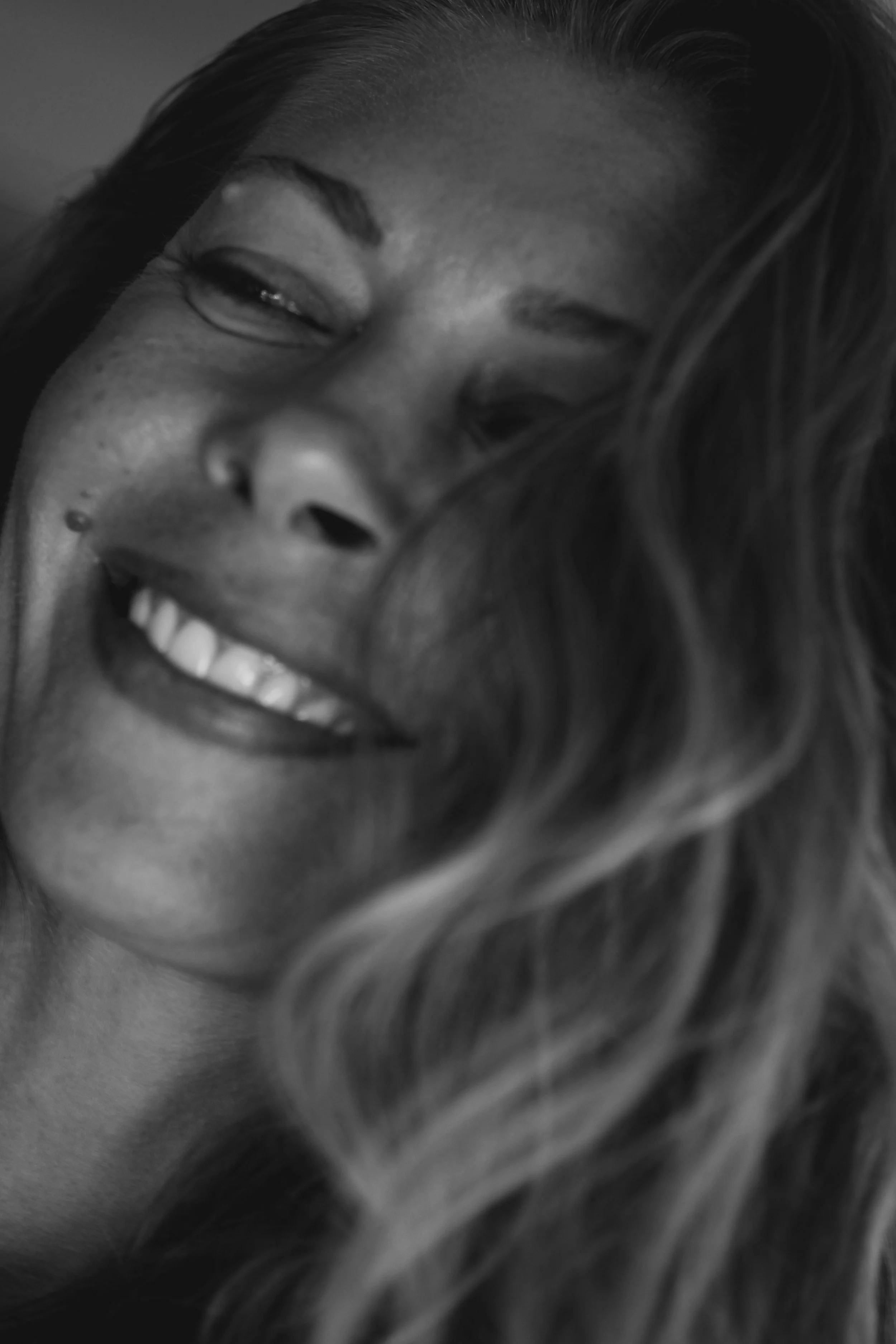 Close-up of a smiling woman with curly hair, black and white photo.