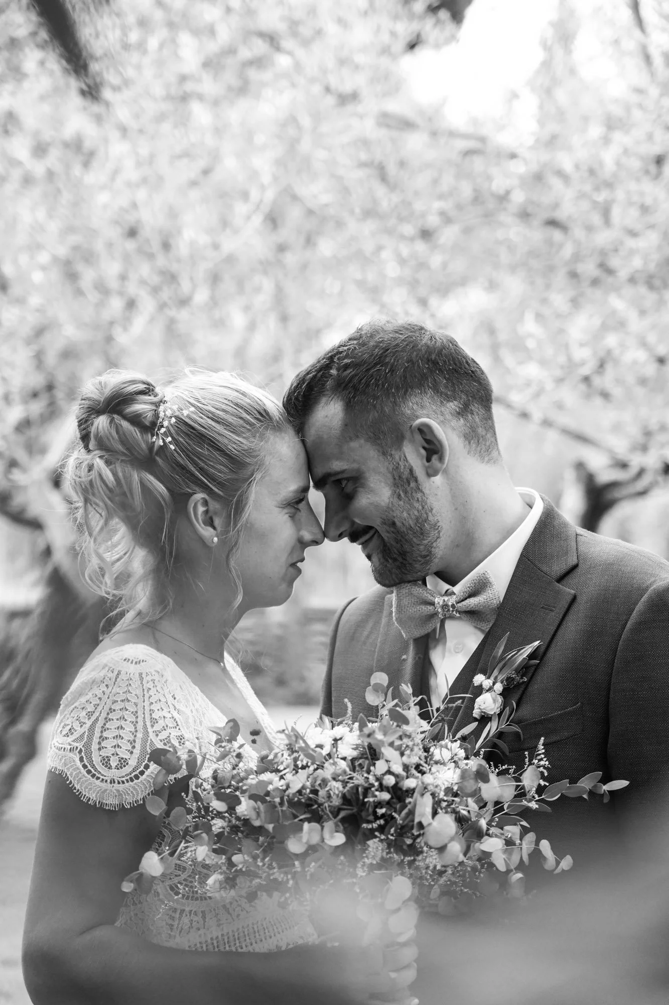 Couple marié se touchant le front, en noir et blanc.