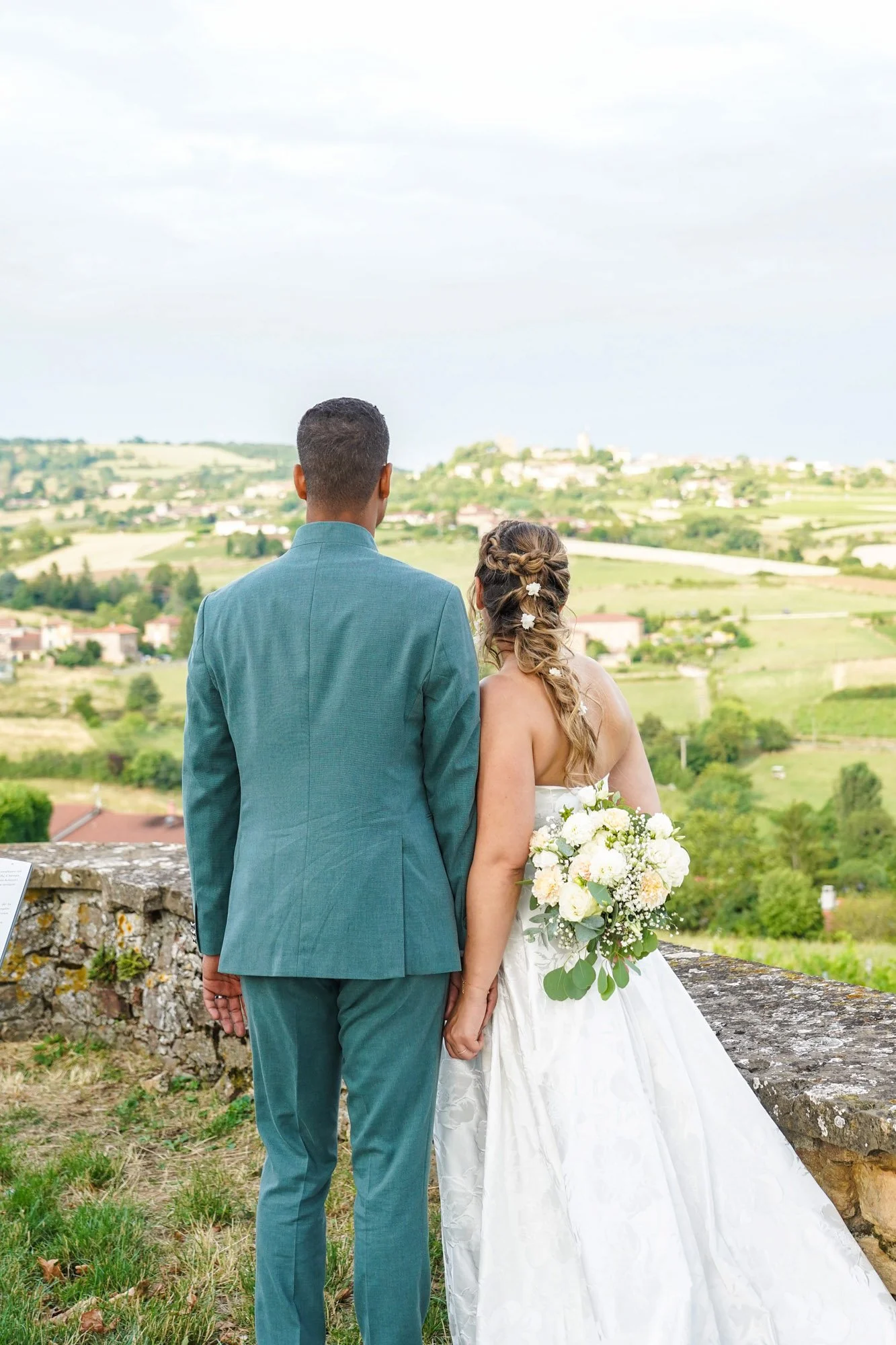 Couple de mariés regardant vers l'horizon lors de leur mariage en extérieur.