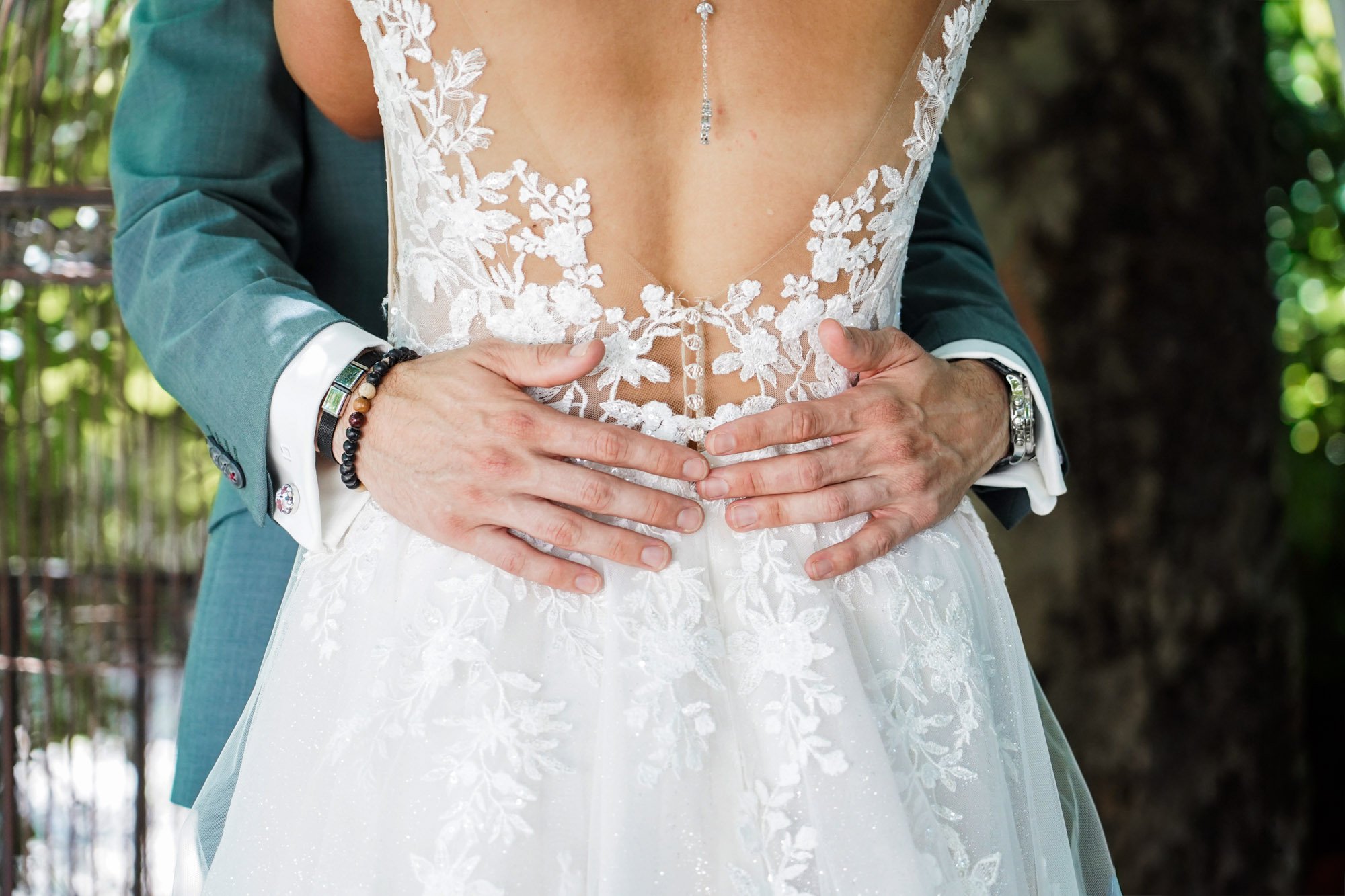 Couple mariés élégants, détails de la robe de mariée avec dentelle florale et un marié en costume bleu canard.
