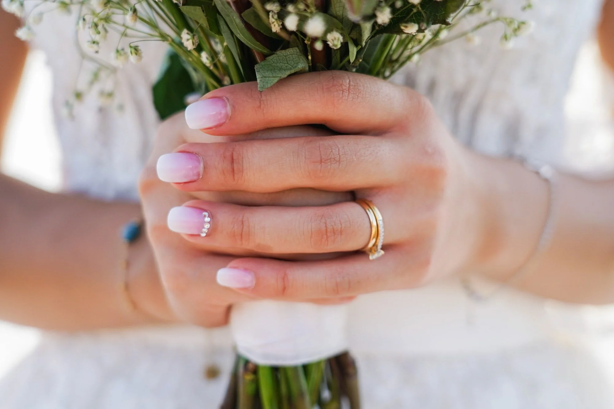Mains mariée tenant un bouquet de fleurs avec alliance.