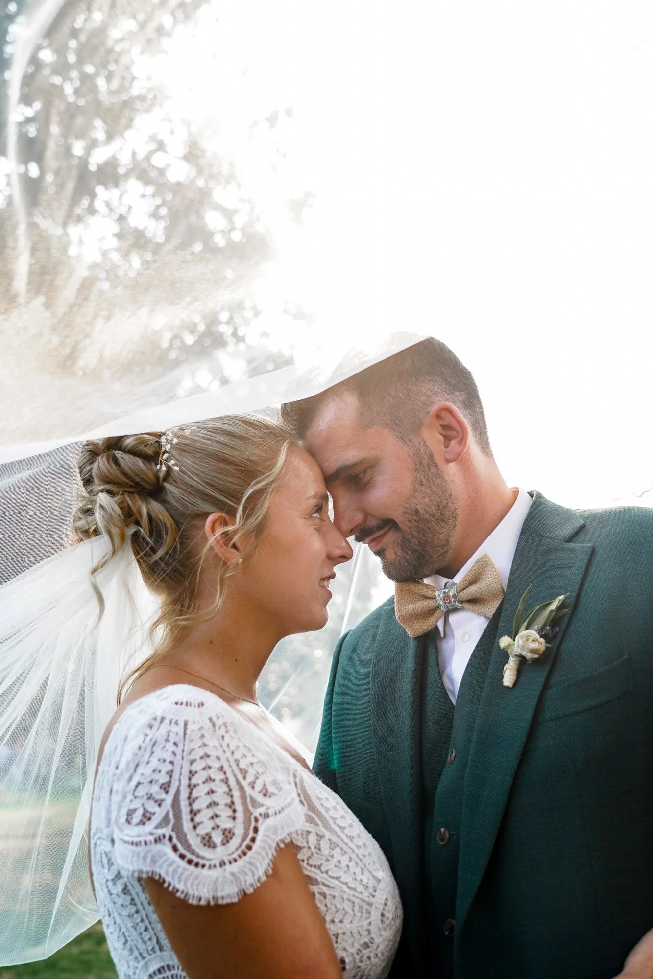 Couple de mariés sous voile de la mariée fronts touchant.