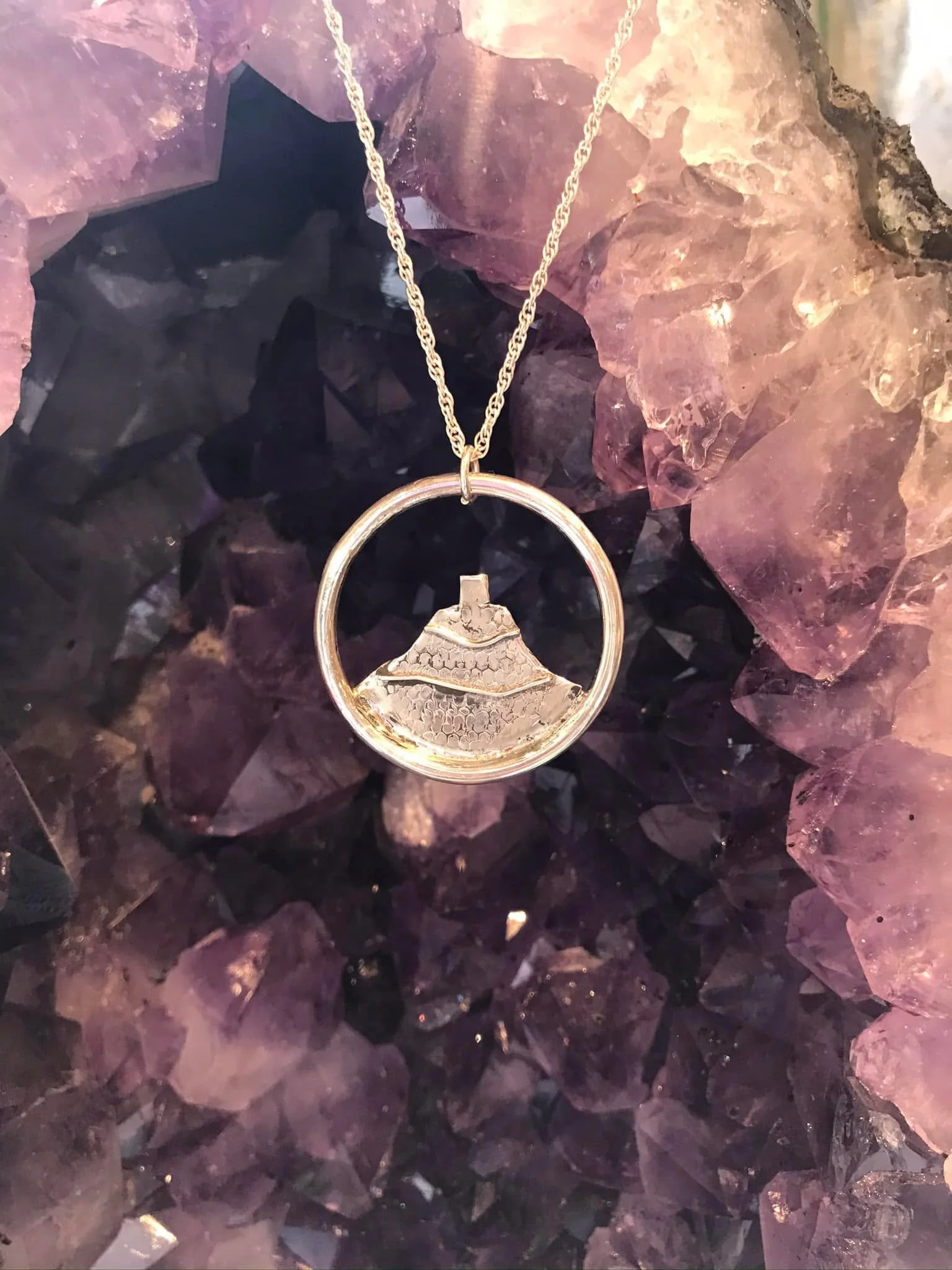 Silver bell in circle necklace against purple amethyst