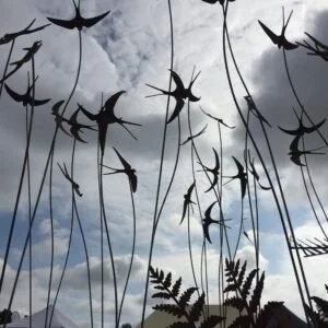 Metal birds on polls against a cloudy sky