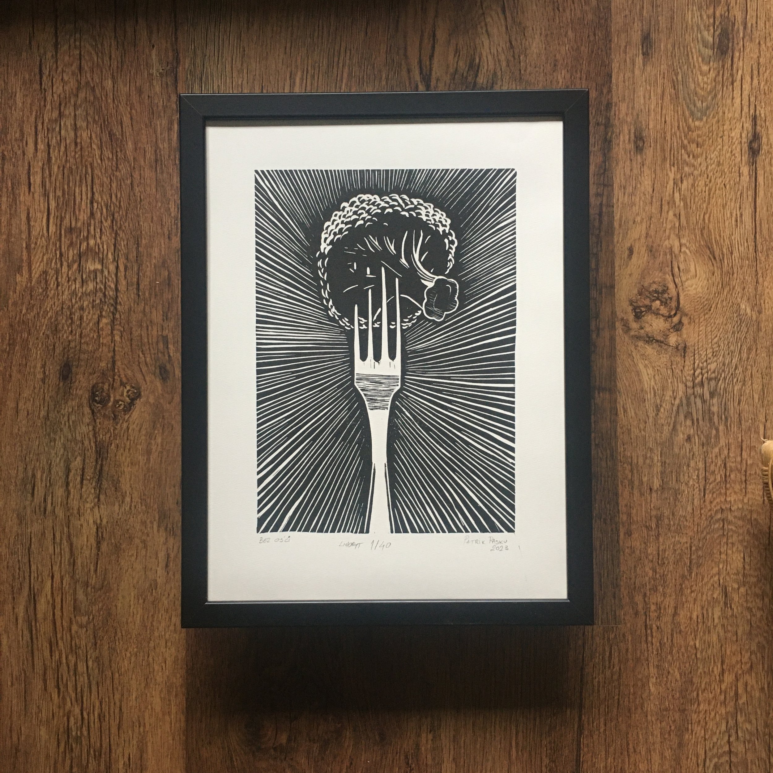 Czarno-biała praca przedstawiająca brokuła z wbitym widelcem, na tle promieniujących linii.--

A black and white artwork depicting a broccoli with a fork through it, set against a radiating lines background.