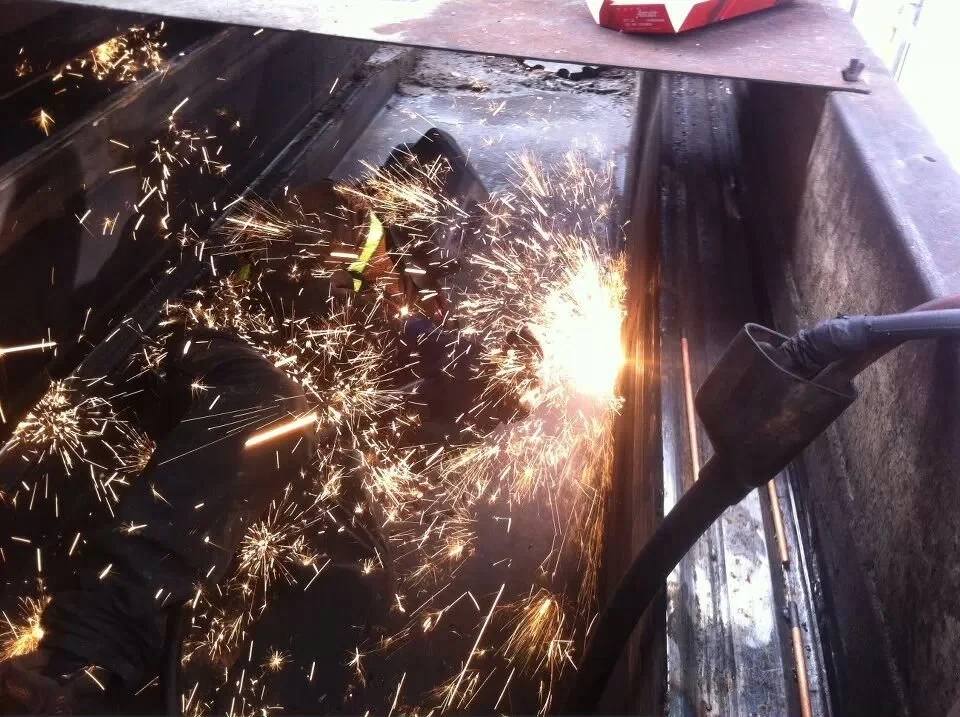 A worker welding metal, sparks flying all around in a workshop or construction site.