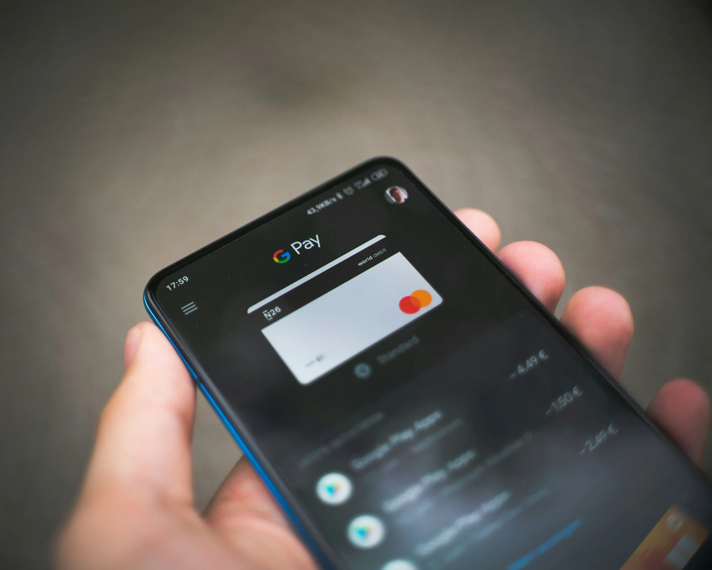 Smartphone displaying Google Pay app with a digital Mastercard credit card on a grey background.