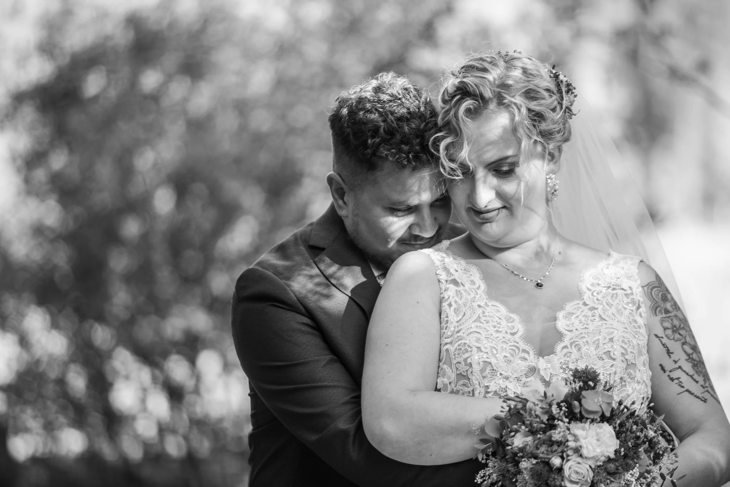Un couple de mariés en étreinte, dans un mariage en plein air, photo en noir et blanc.