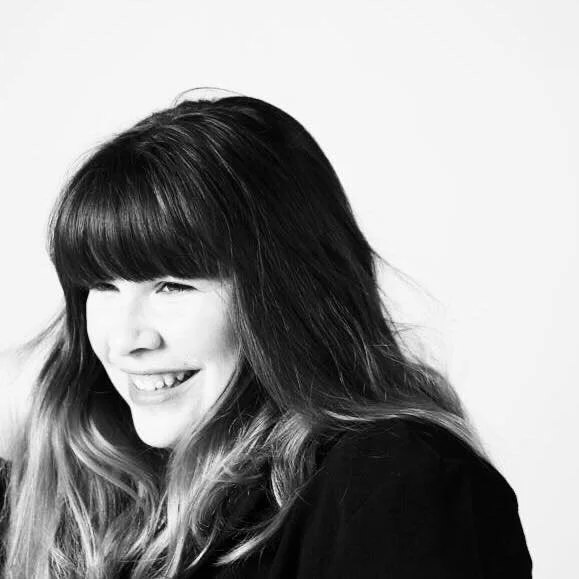 Portrait en noir et blanc d'une femme souriante avec des cheveux longs et bouclés.