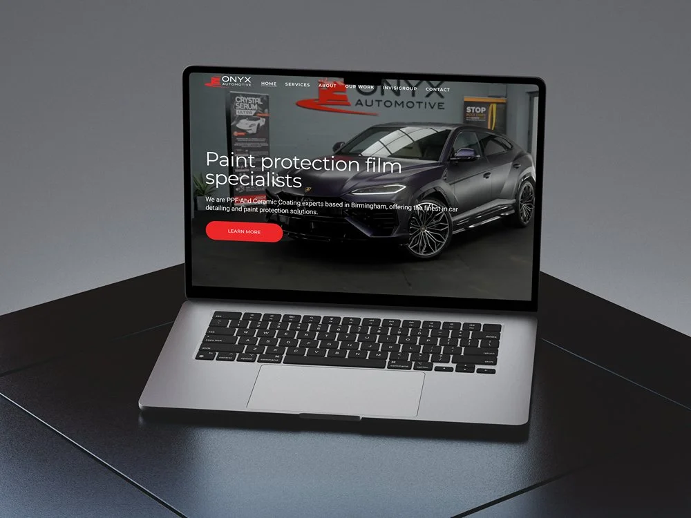 Laptop displaying a website for Onyx Automotive, featuring a dark-colored sports car and information about paint protection film specialists.