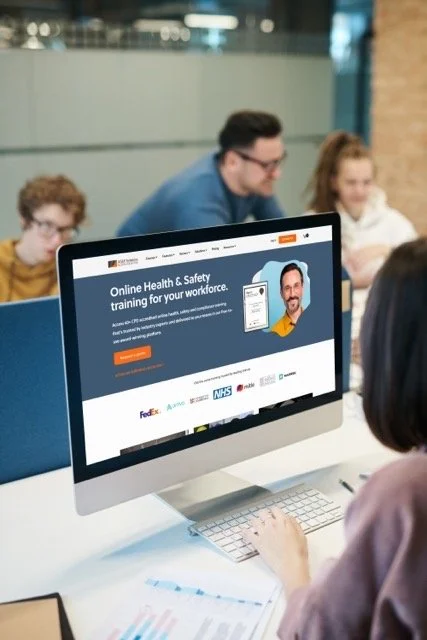 Person using a computer displaying an online health and safety training website in a classroom setting.