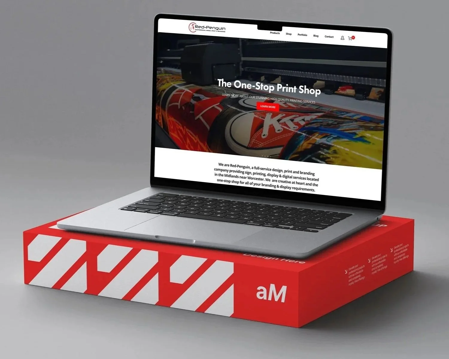 A laptop displaying a website on a red and white striped box, with the website showing a print shop offering high-quality printing services.