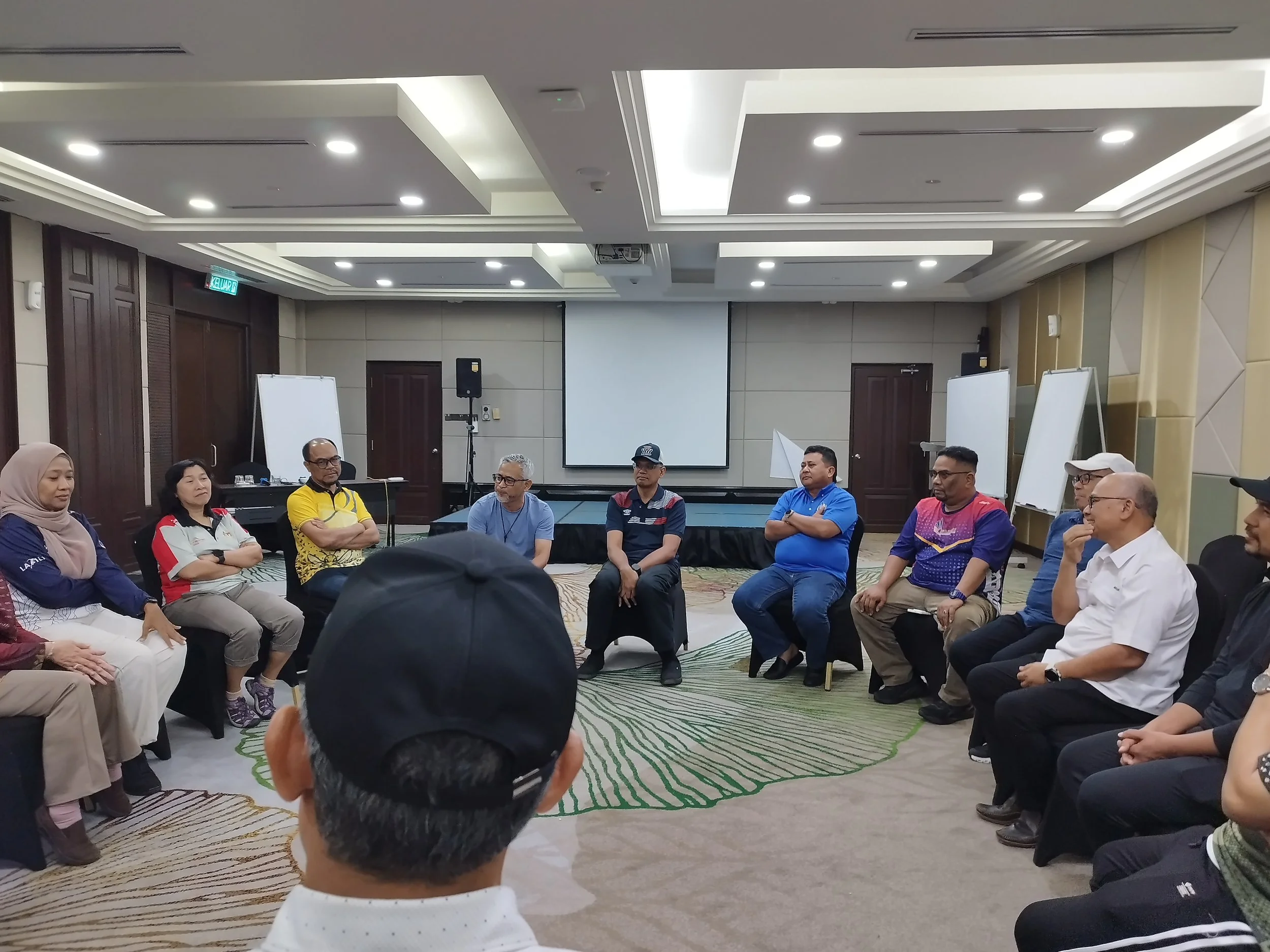 A group of people sitting in a circle in a conference room, participating in a discussion or workshop.