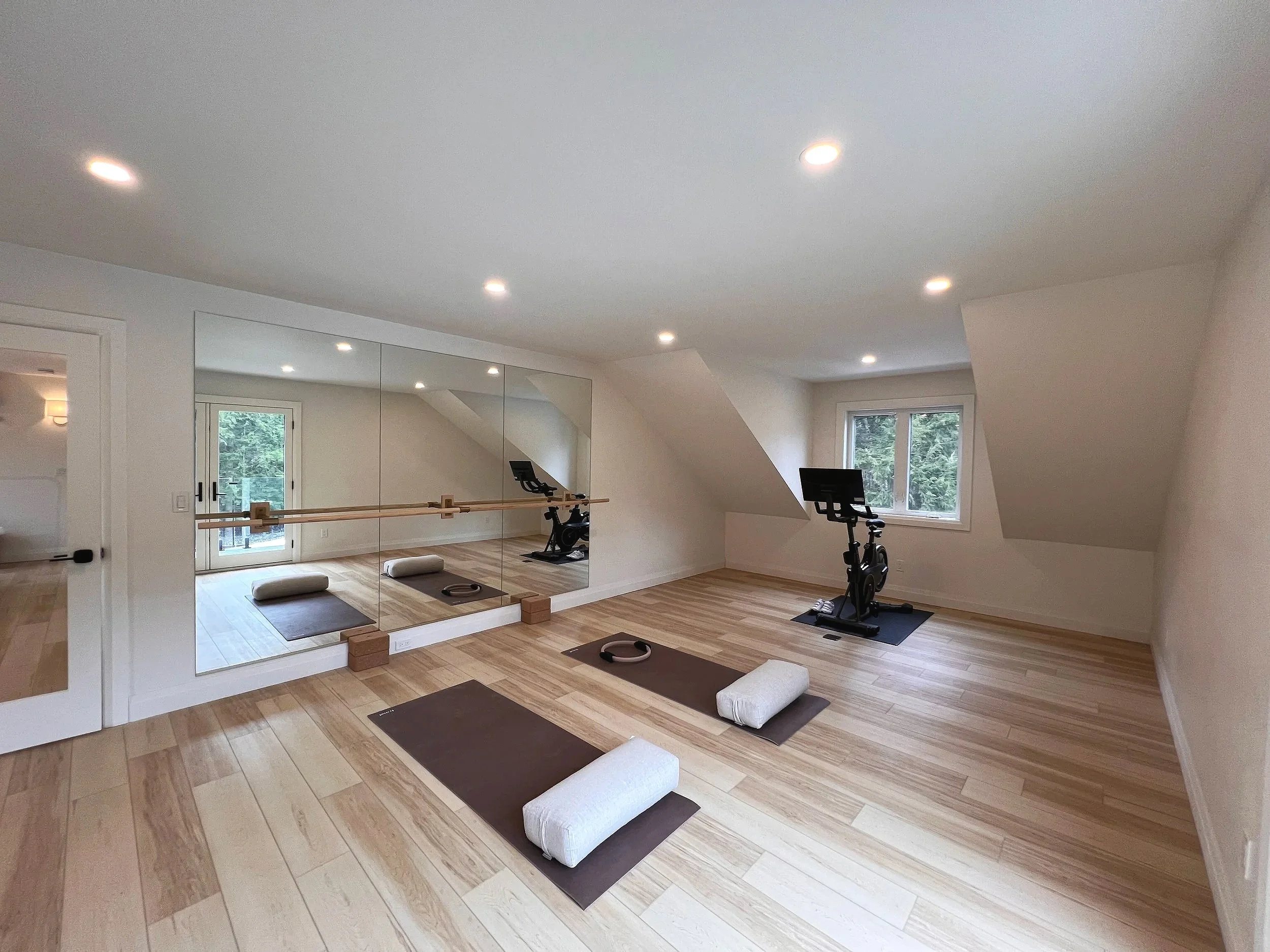Home gym with custom mirrors and wall-mounted ballet barre. Custom wood surrounds for brackets help maintain continuity throughout the design. 
