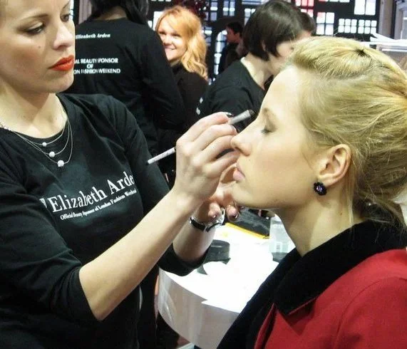 Makeup artist Cecilia Acquaroli, applying makeup to a woman seated at London Fashion Week