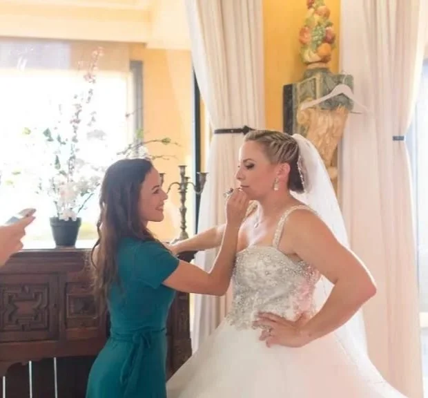 Professional stylist Cecilia Acquaroli providing a calm makeup touch-up for a bride in a sun-filled suite. With over 15 years of experience in bridal styling, she focuses on creating a grounded, personal environment for her clients on their wedding