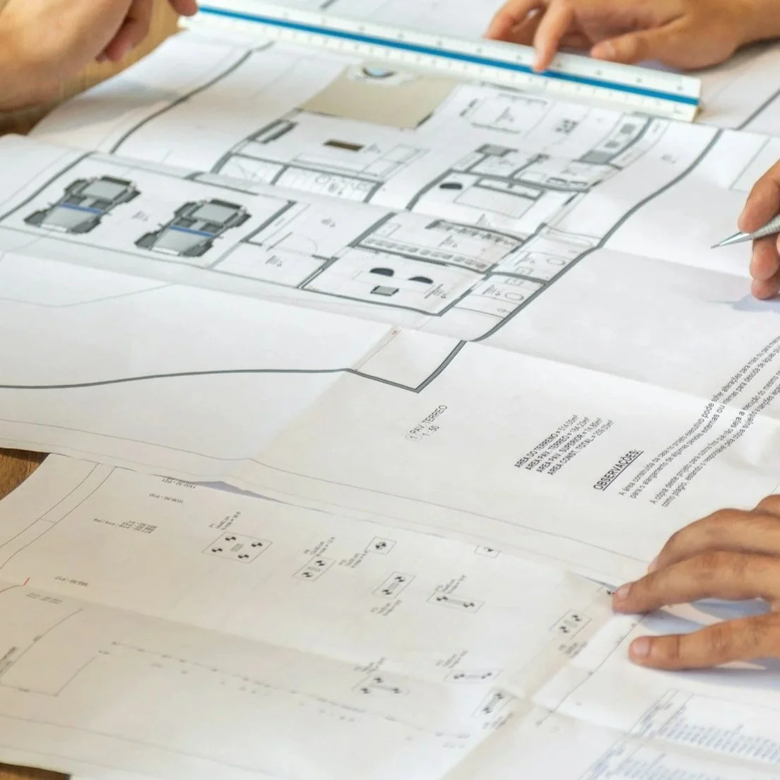 People examining architectural blueprints and floor plans on a table.