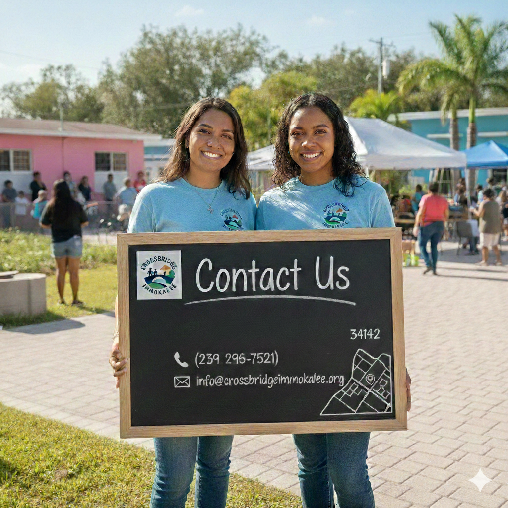 Two women holding a large contact information sign at an outdoor event with people, food booths, and trees in the background.