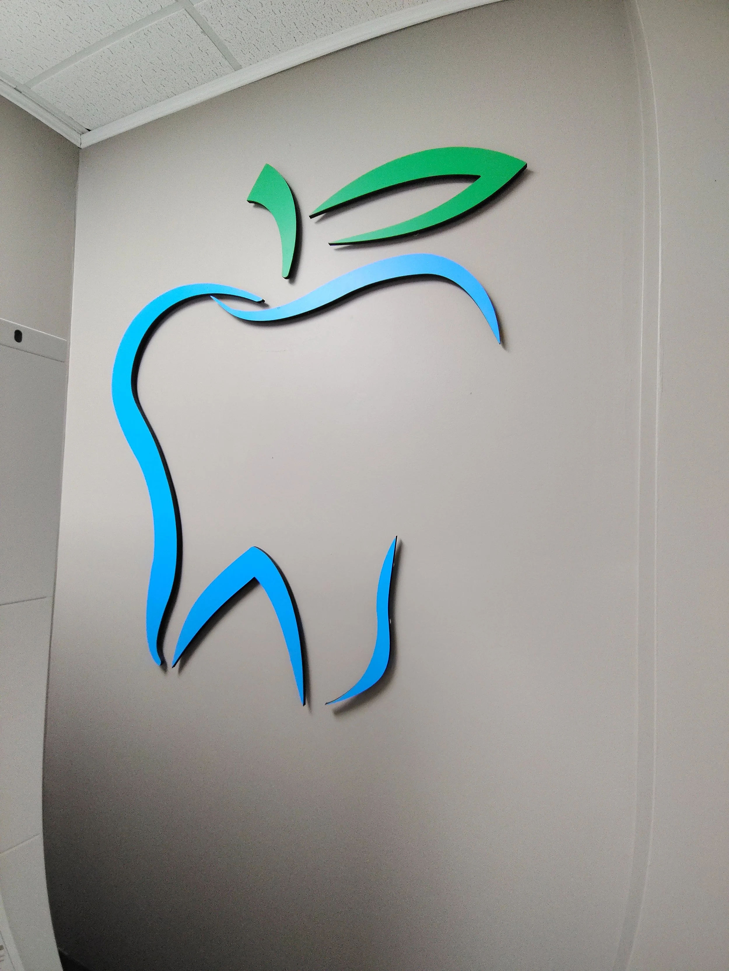 A stylized modern logo featuring an abstract blue and green apple outline on a light gray wall.