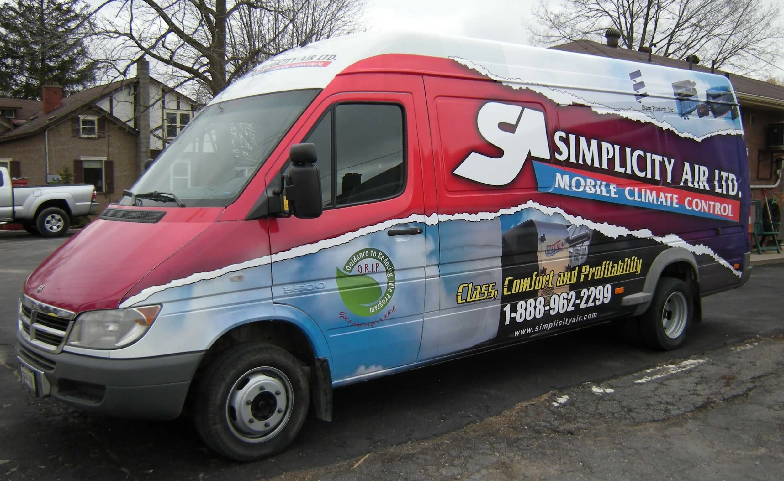 A vehicle used for advertising parked on a street with houses in the background. It has a colorful wrap for Simplicity Air Ltd, a company specializing in mobile climate control, with text highlighting class, comfort, and profitability.