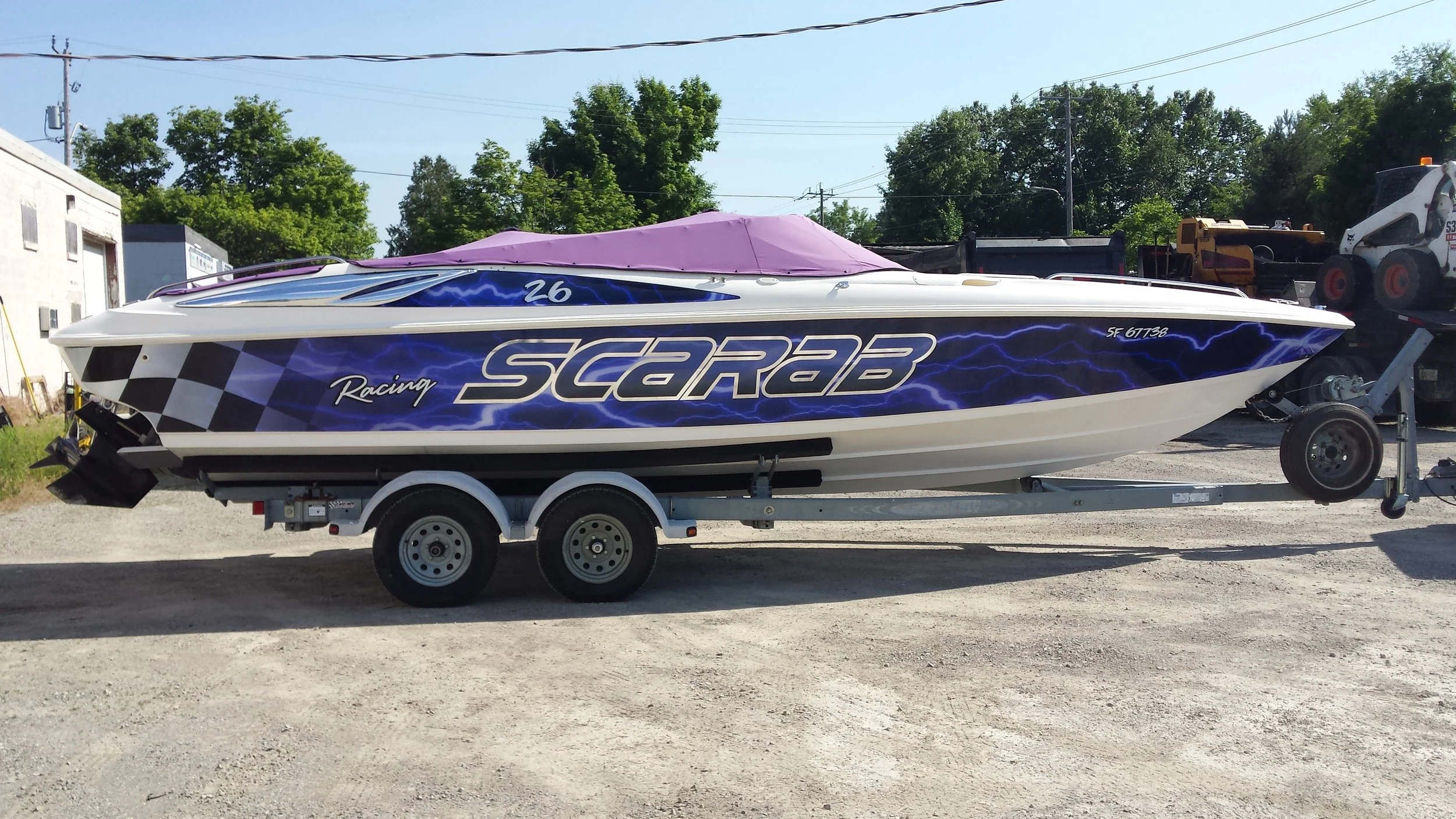 Speedboat on a trailer with vibrant blue and black lightning graphics, purple canopy, and racing decals.