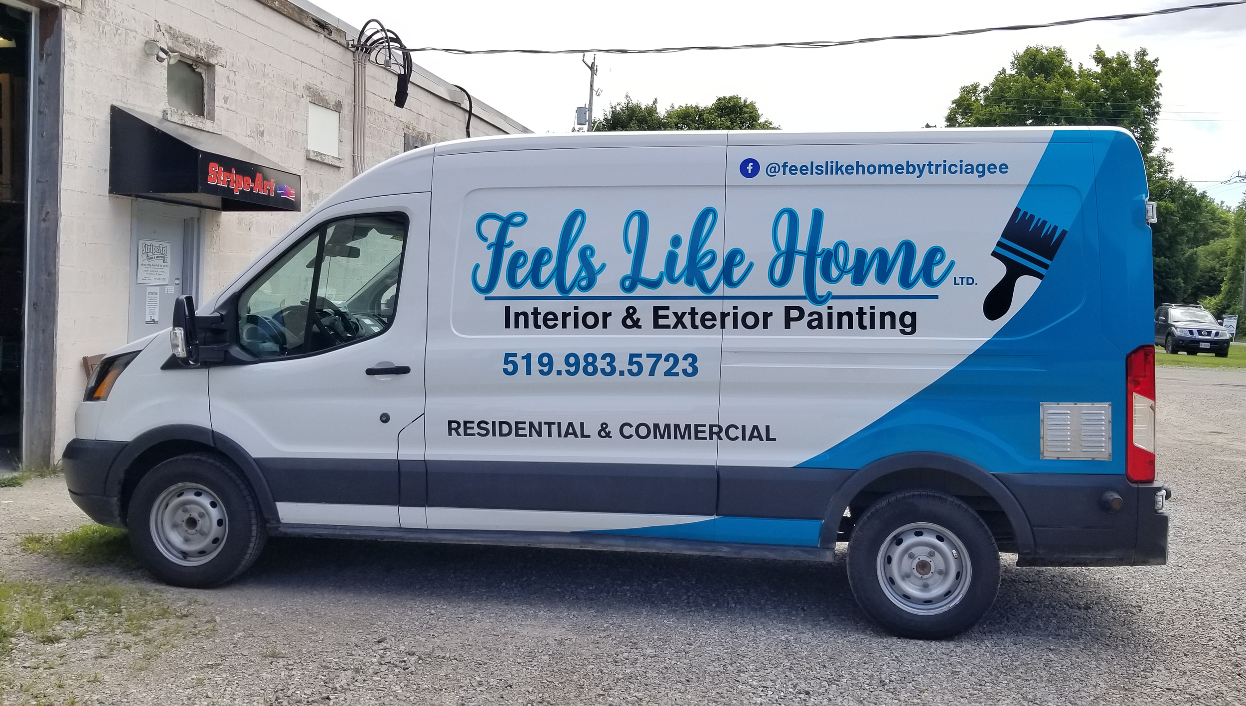 White commercial van parked on gravel with branding for Feels Like Home interior and exterior painting, including a blue paintbrush graphic, contact number, and social media handle.