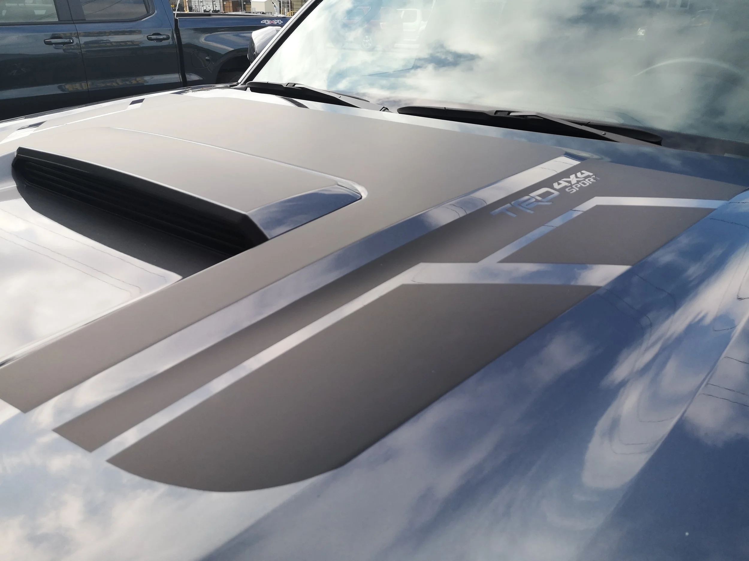 Close-up of a vehicle's hood with a black vent and decal stickers reading 'TRD 4x4 SPORT' and 'Toyota Racing Development'.