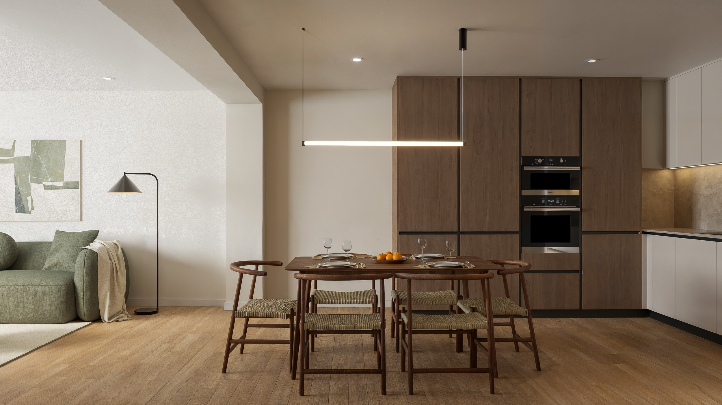 Modern open-concept living room and dining area with a wooden dining table, six chairs, a green sofa, a floor lamp, and built-in kitchen cabinets with appliances.