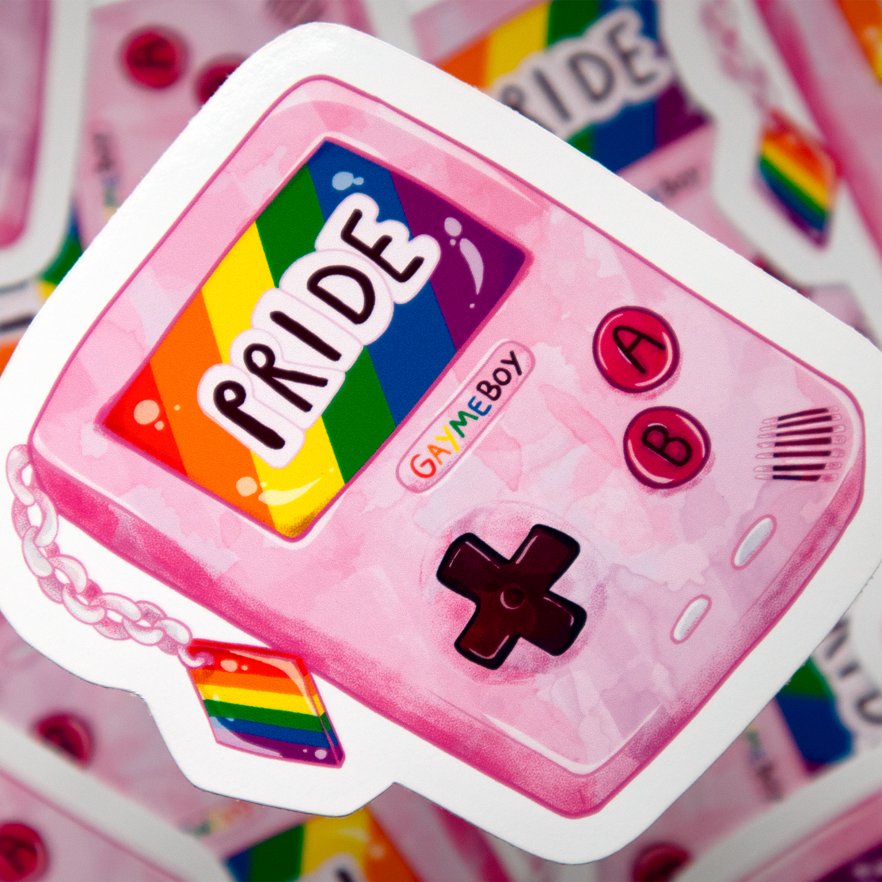 A pink Game Boy style gaming device with a rainbow flag and a 'PRIDE' label, featuring buttons labeled A and B and a directional pad.